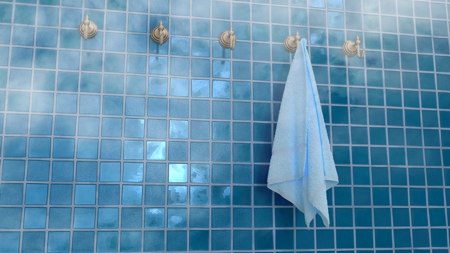 Une serviette éponge sur l'un des nombreux crochet d'un mur carrelet de petits carreaux